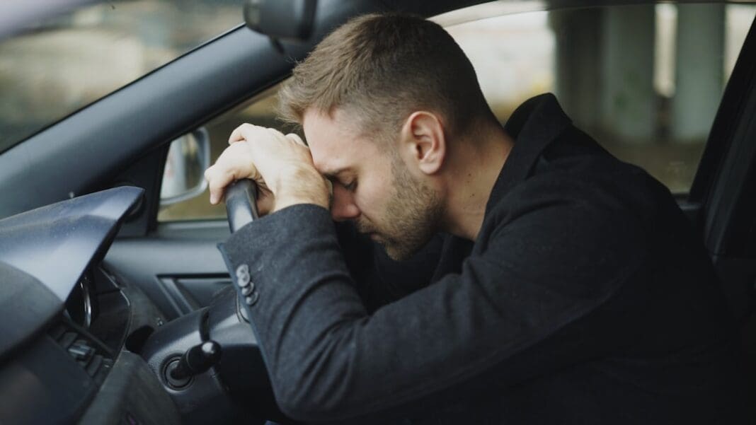 Man resting head on steering wheel in car. | Photo by Vitaly Gariev on Unsplash