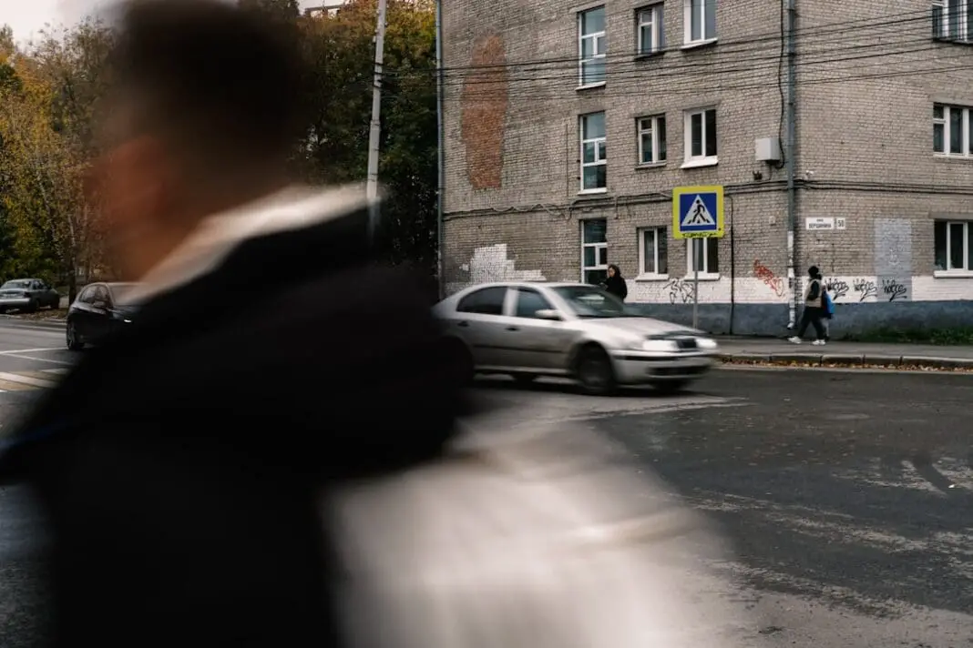 People crossing street near building and car