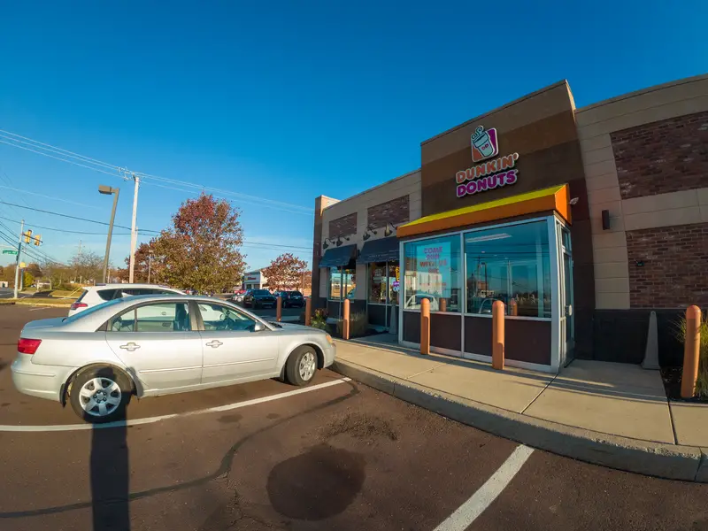 A car is parked in front of a Dunkin Donuts store