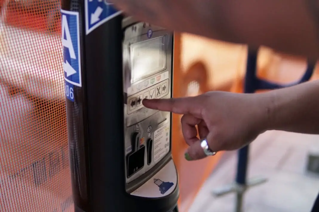 Some one adding time to a parking meter for street parking.