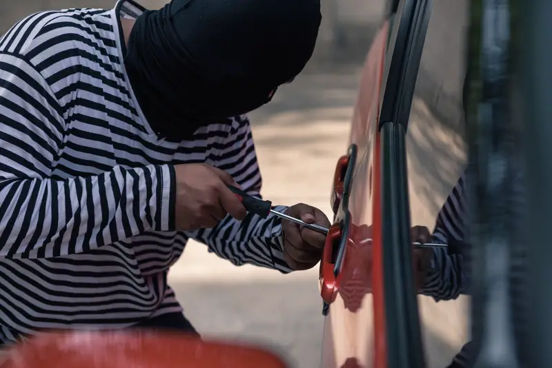 Car thief trying to unlock a car by screwdriver