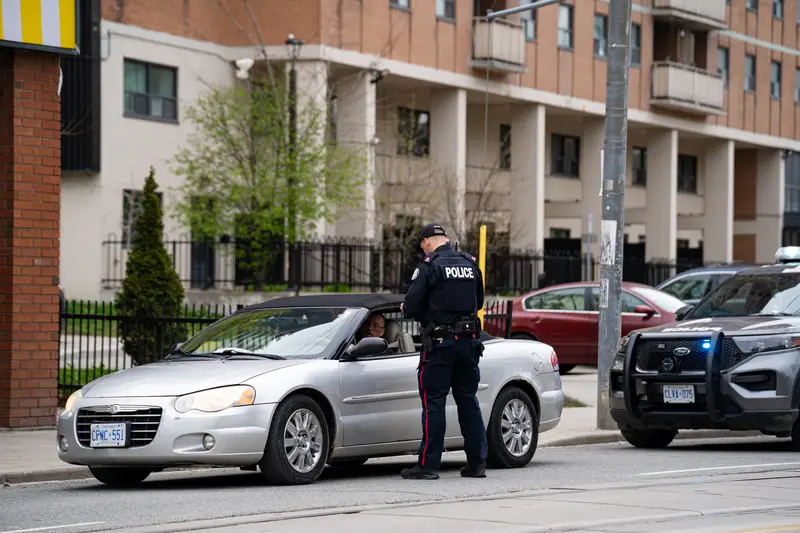 Police officer conducting traffic stop with driver on city street.